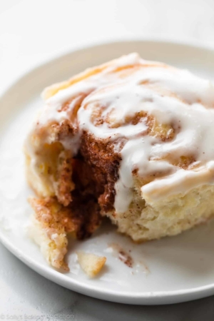 Cinnamon roll with vanilla icing on a white plate