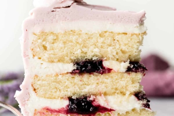 Slice of lavender butter cake with purple frosting and blackberry jam