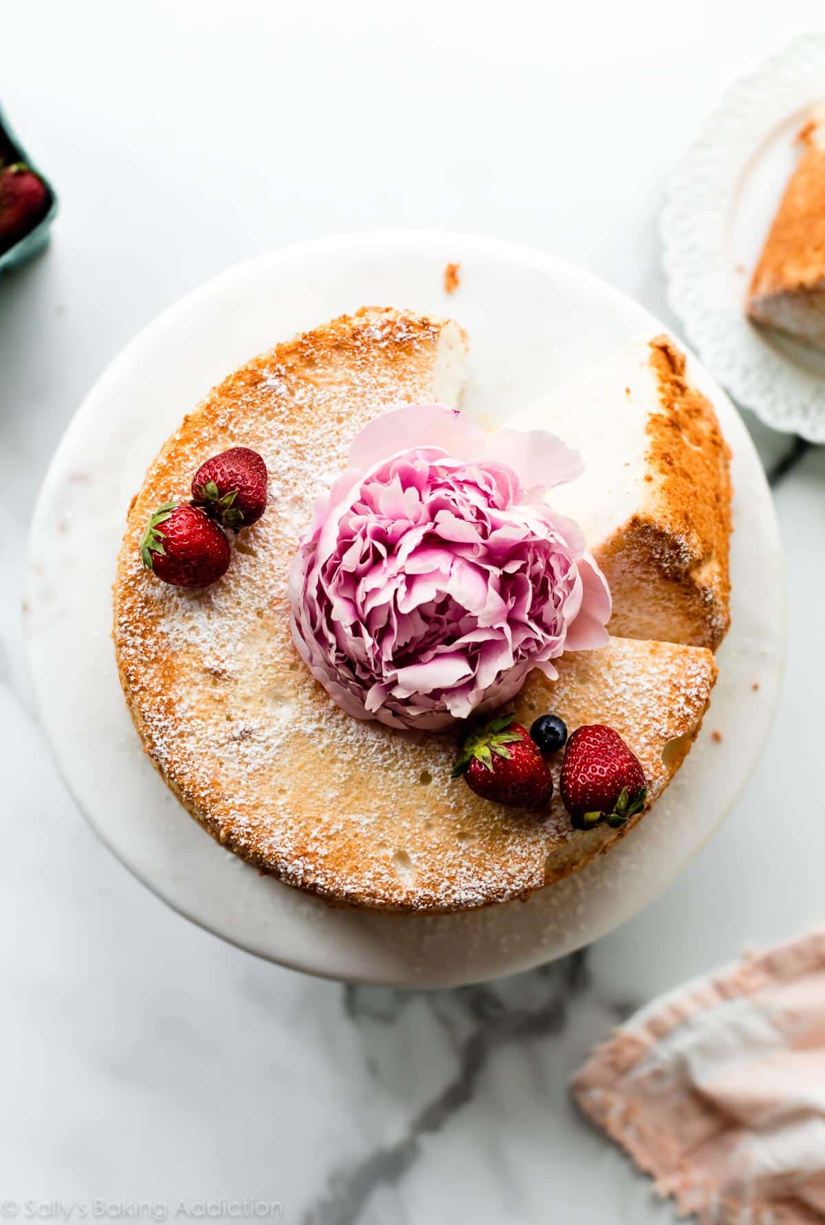 Top of angel food cake with berries and pink peony flower