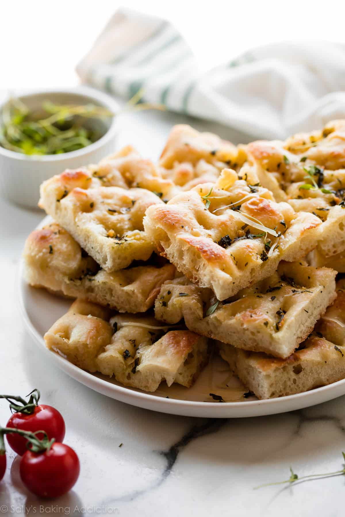 Garlic rosemary herb focaccia bread on white serving plate