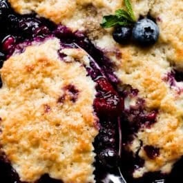 mixed berry cobbler with a serving spoon