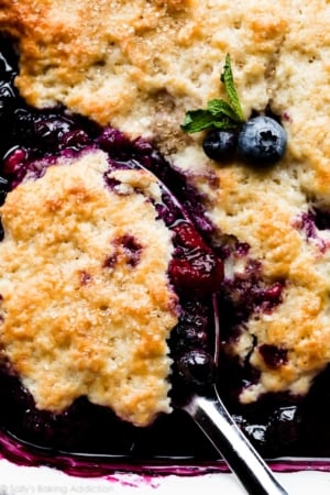 mixed berry cobbler with a serving spoon
