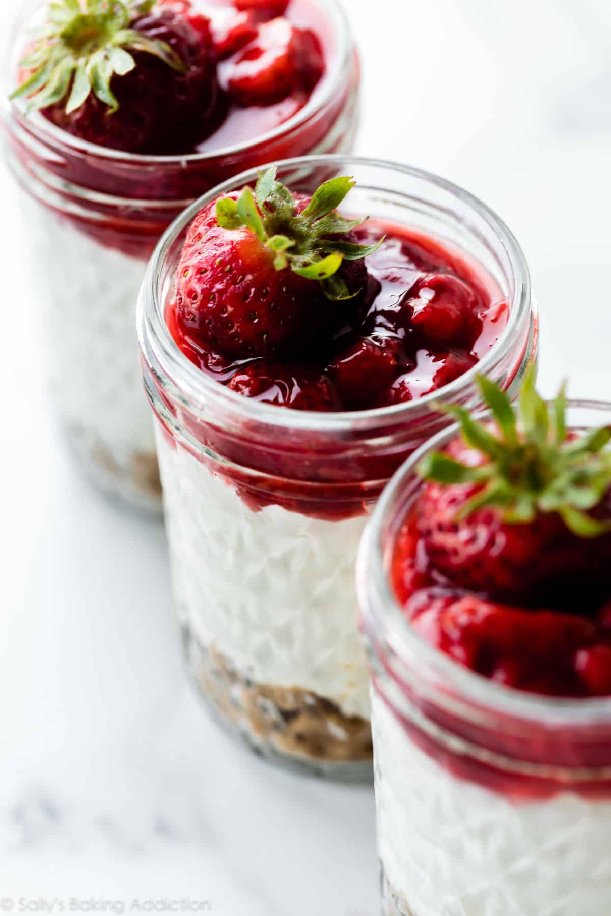 jars of individual no bake cheesecakes with strawberry topping