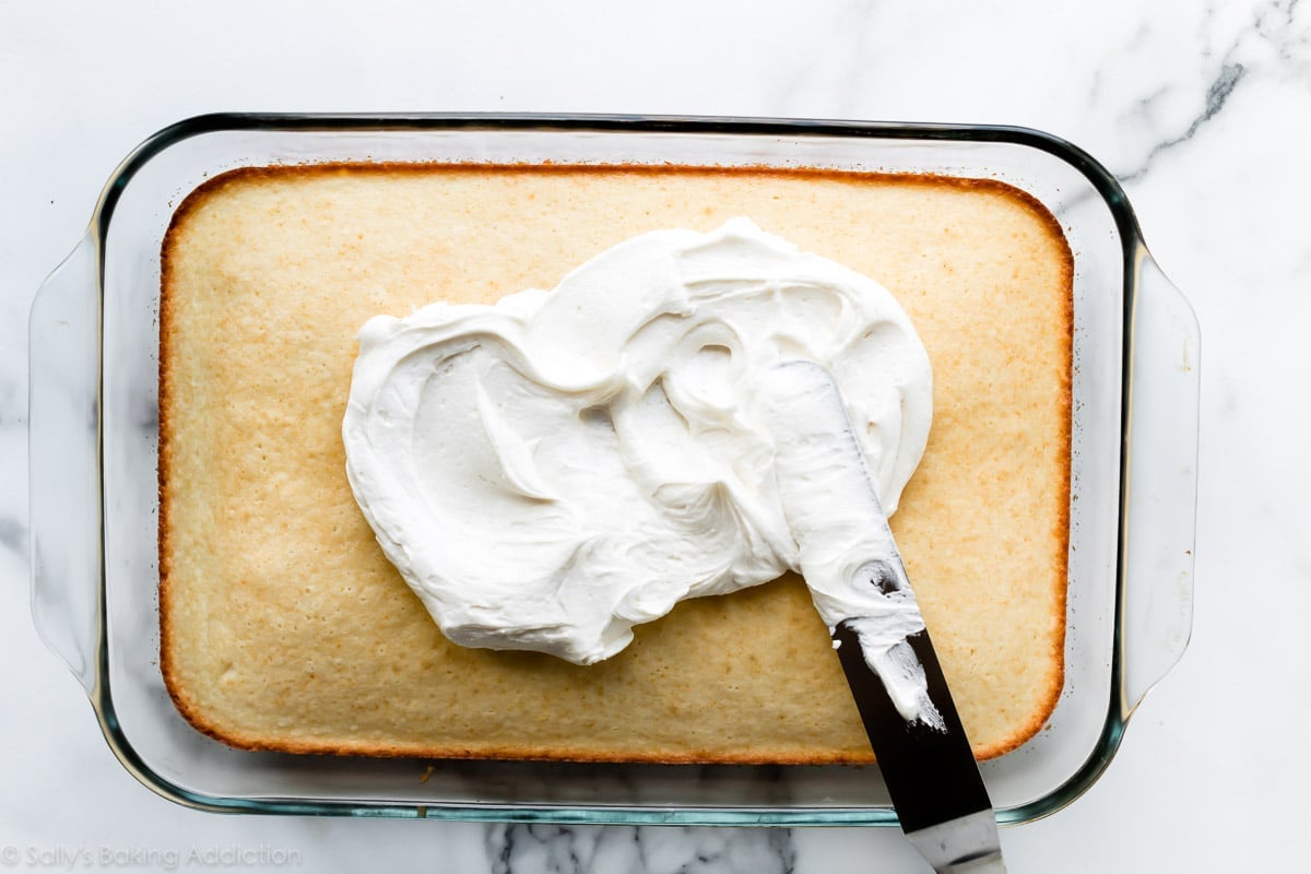spreading frosting onto vanilla sheet cake with vanilla buttercream