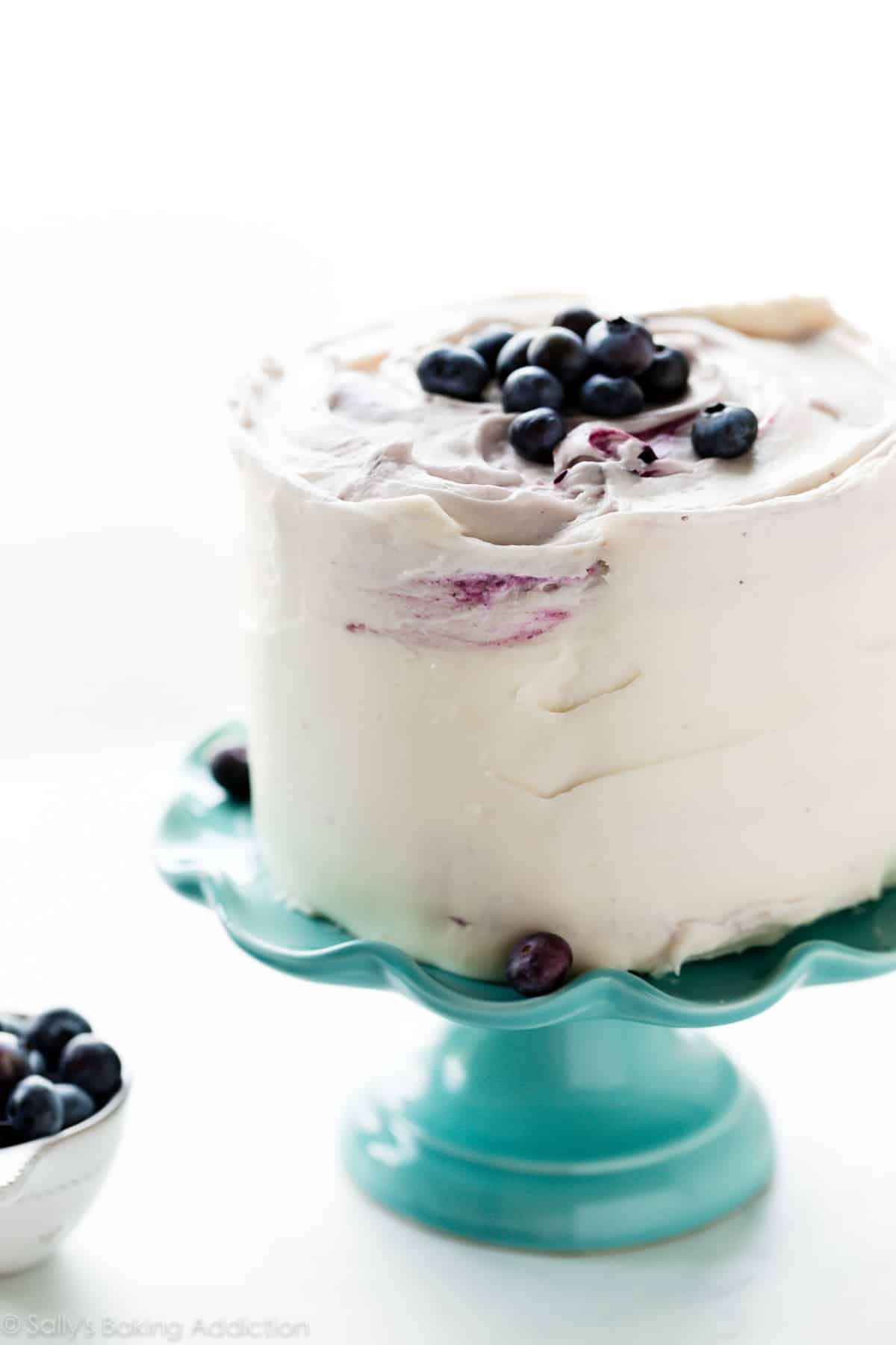 vanilla sponge vertical cake with lemon blueberry whipped cream on teal cake stand