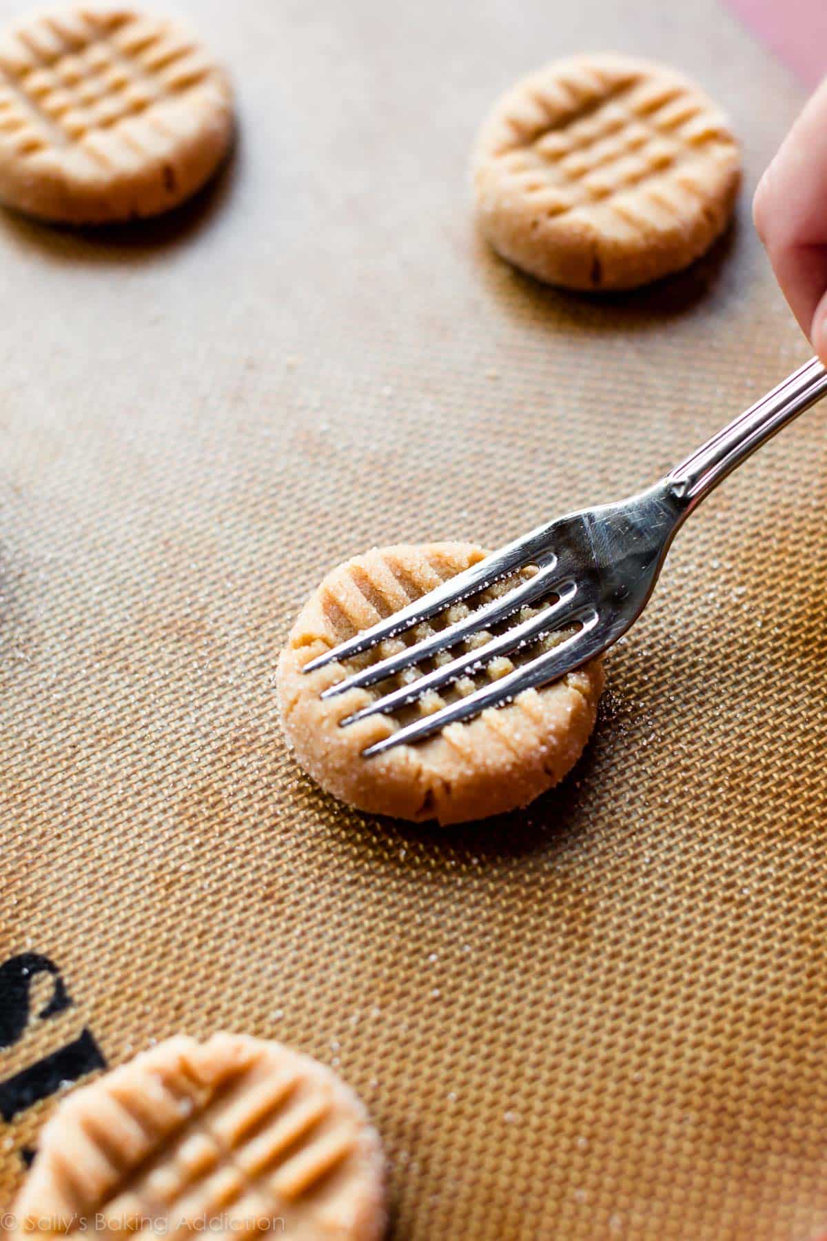 adding a criss cross to peanut butter cookies with a fork