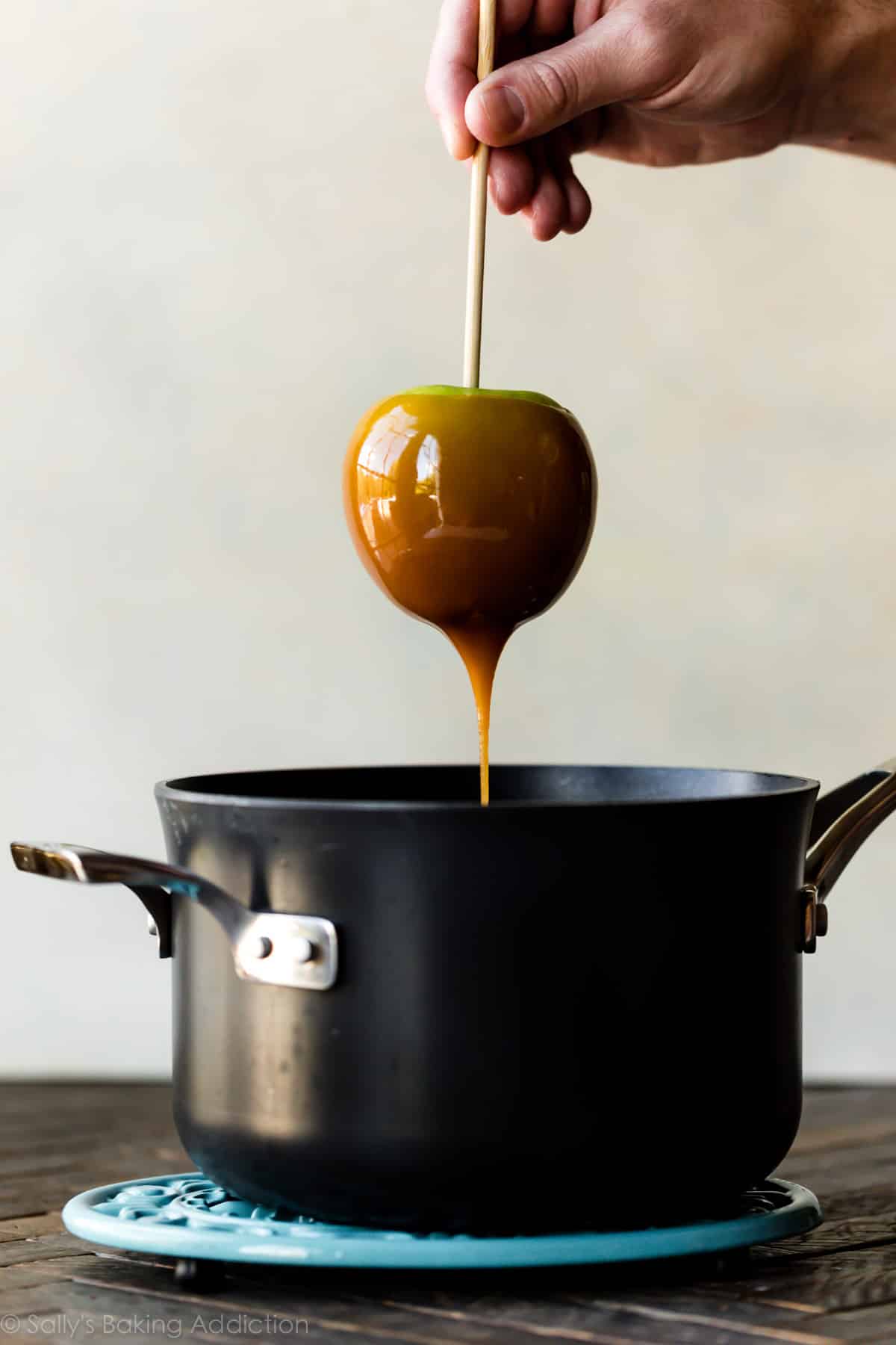dipping apple into a pot of caramel