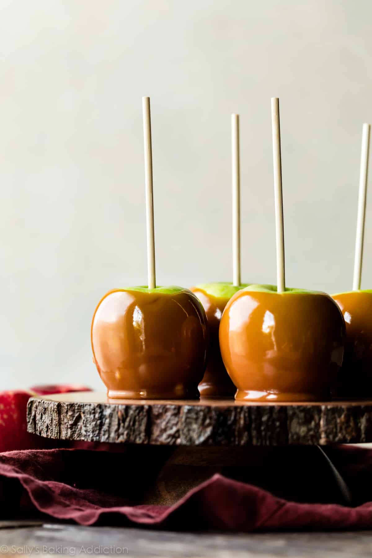 homemade caramel apples on a wood slice cake stand