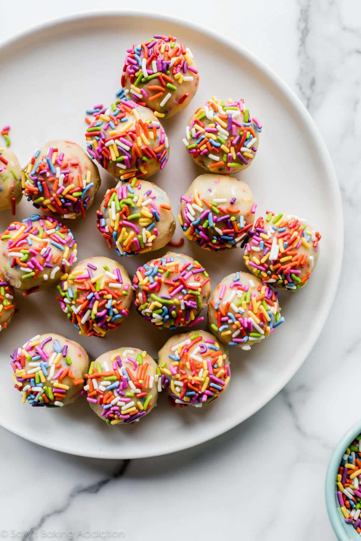 sprinkle sugar cookie dough rolled into balls on a white plate
