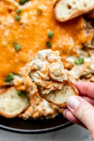 hand holding baguette slice dipped in Maryland crab dip.