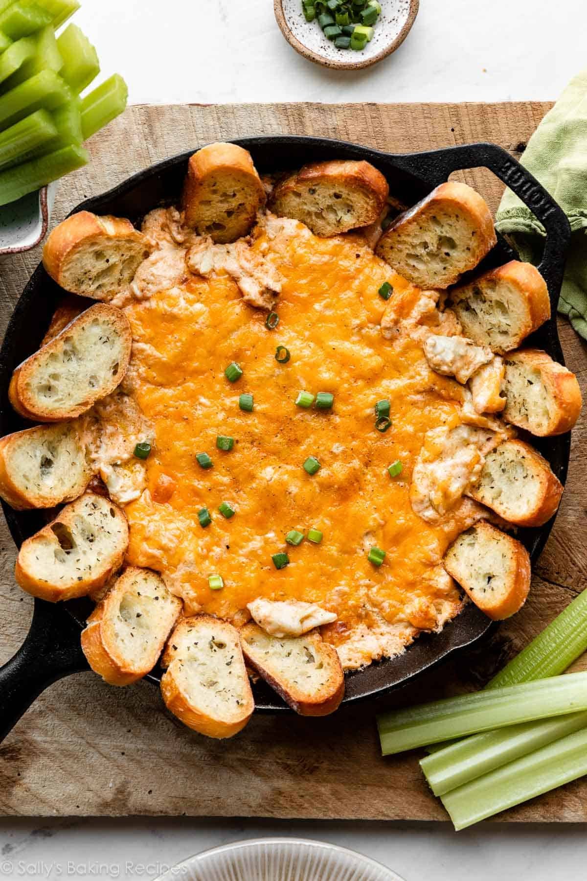crab dip in cast iron skillet with toasted baguette slices around the edges.