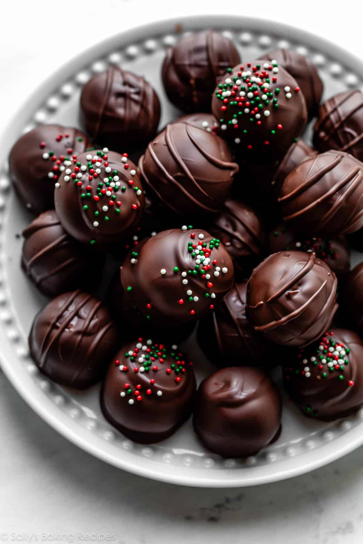 plate of peanut butter balls candies coated in chocolate and some pictured with Christmas sprinkles on top.