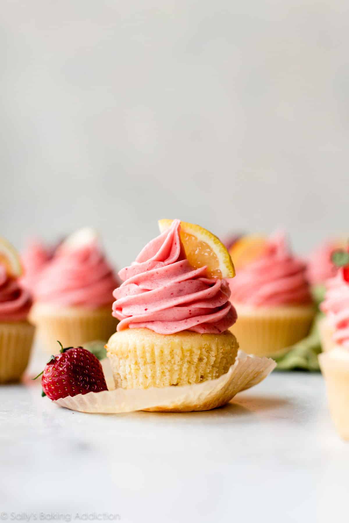 unwrapped lemon cupcake with pink strawberry frosting on top