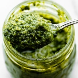 spoonful of homemade basil pesto coming out of a jar.