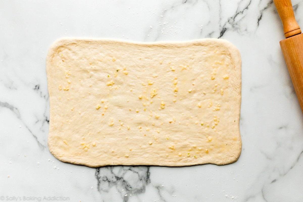 dough in the shape of a rectangle with butter and garlic spread on top