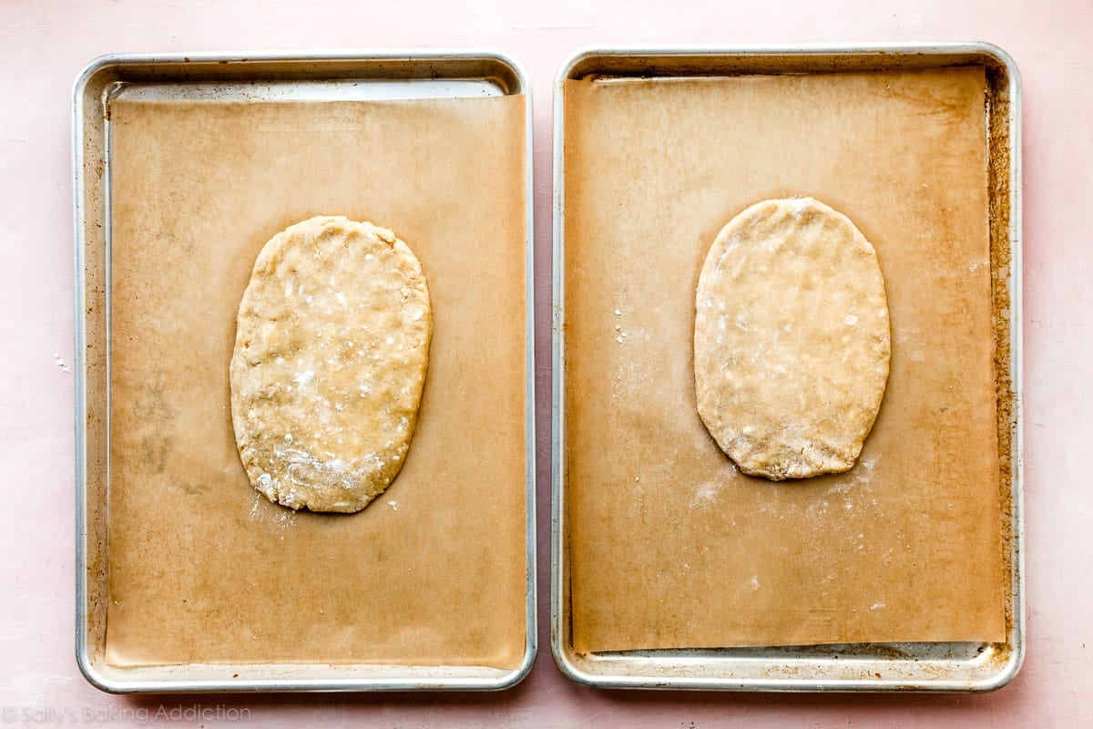 two baking sheets each with a slab of biscotti dough before baking
