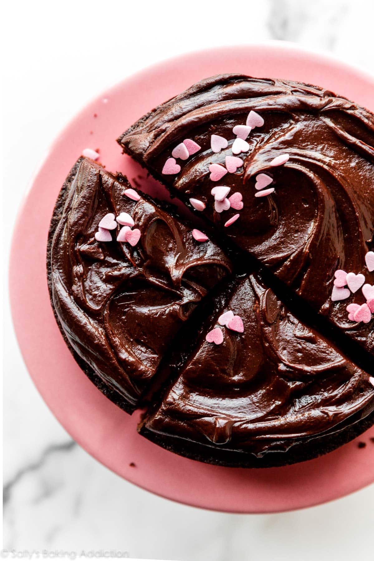 foto de arriba de ganache de chocolate y corazón rosa rociado en pastel de chocolate