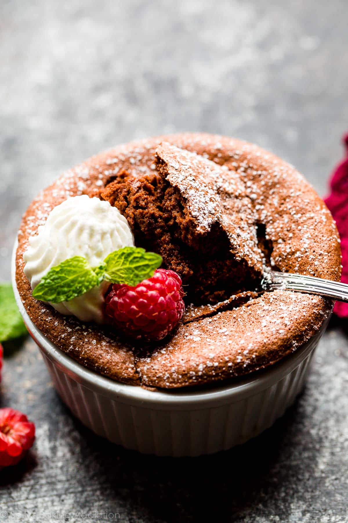 spoonful of warm chocolate souffle with a raspberry and whipped cream on top