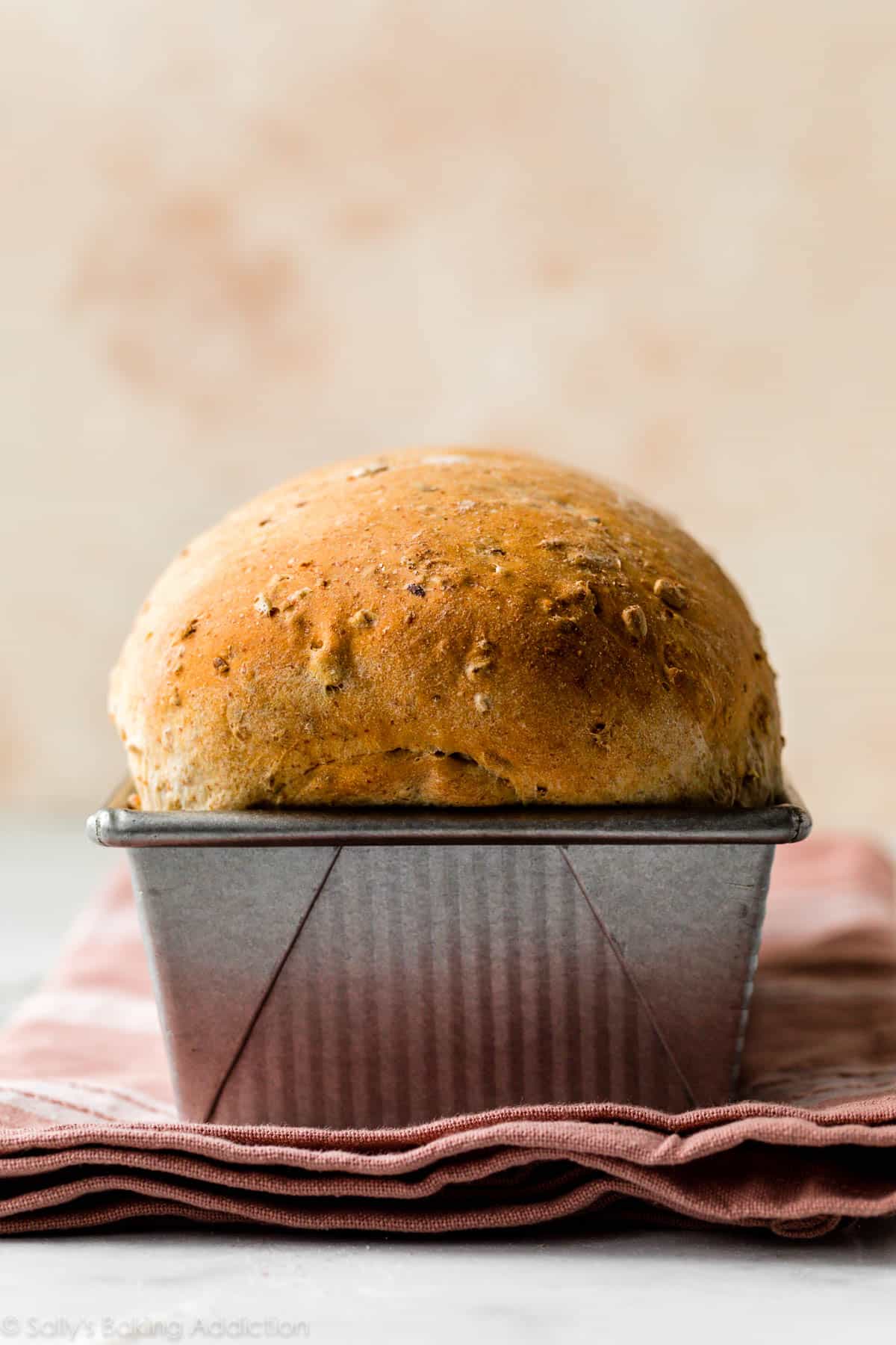 multigrain bread in loaf pan on pink linen napkin