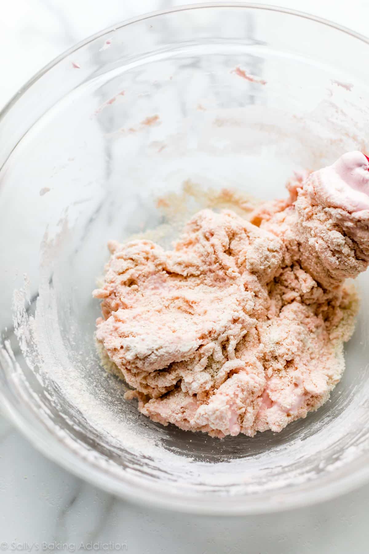folding pink tinted beaten egg whites into almond flour and confectioners' sugar