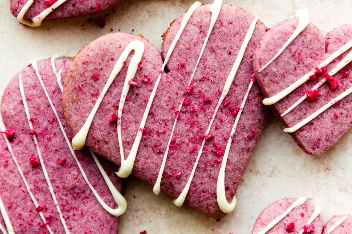 heart-shaped raspberry cookies with white chocolate drizzle on top