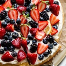 lemon berry dessert fruit pizza with strawberries, blackberries, blueberries, and a lemon slices on top.