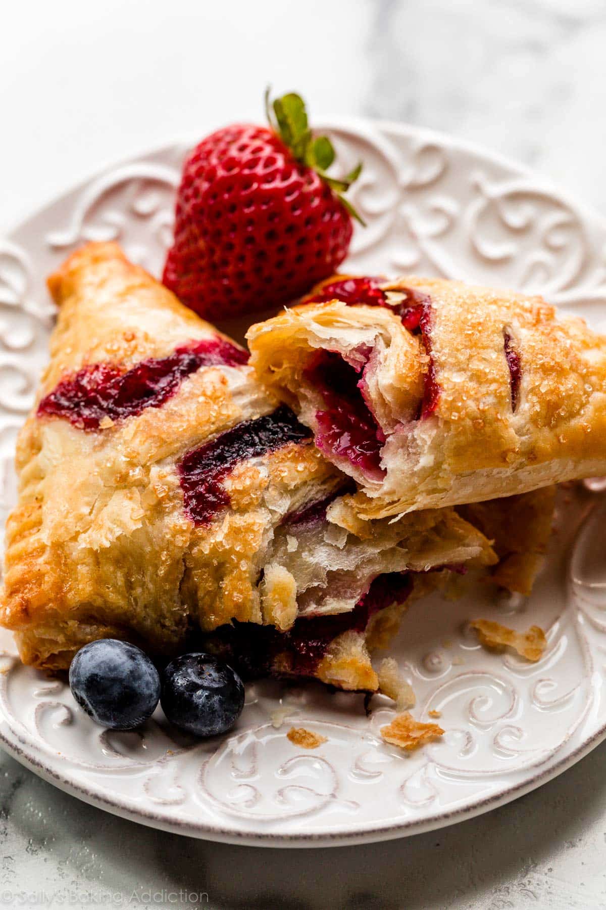 mixed berry turnovers on plate with extra flaky homemade puff pastry