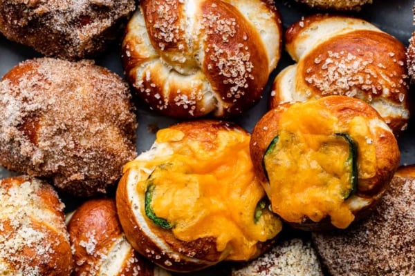 soft pretzel knots with different toppings including garlic parmesan, cinnamon sugar, and jalapeño cheddar