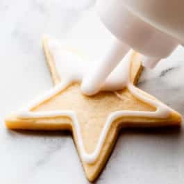 decorating a sugar cookie with white icing using a squeeze bottle