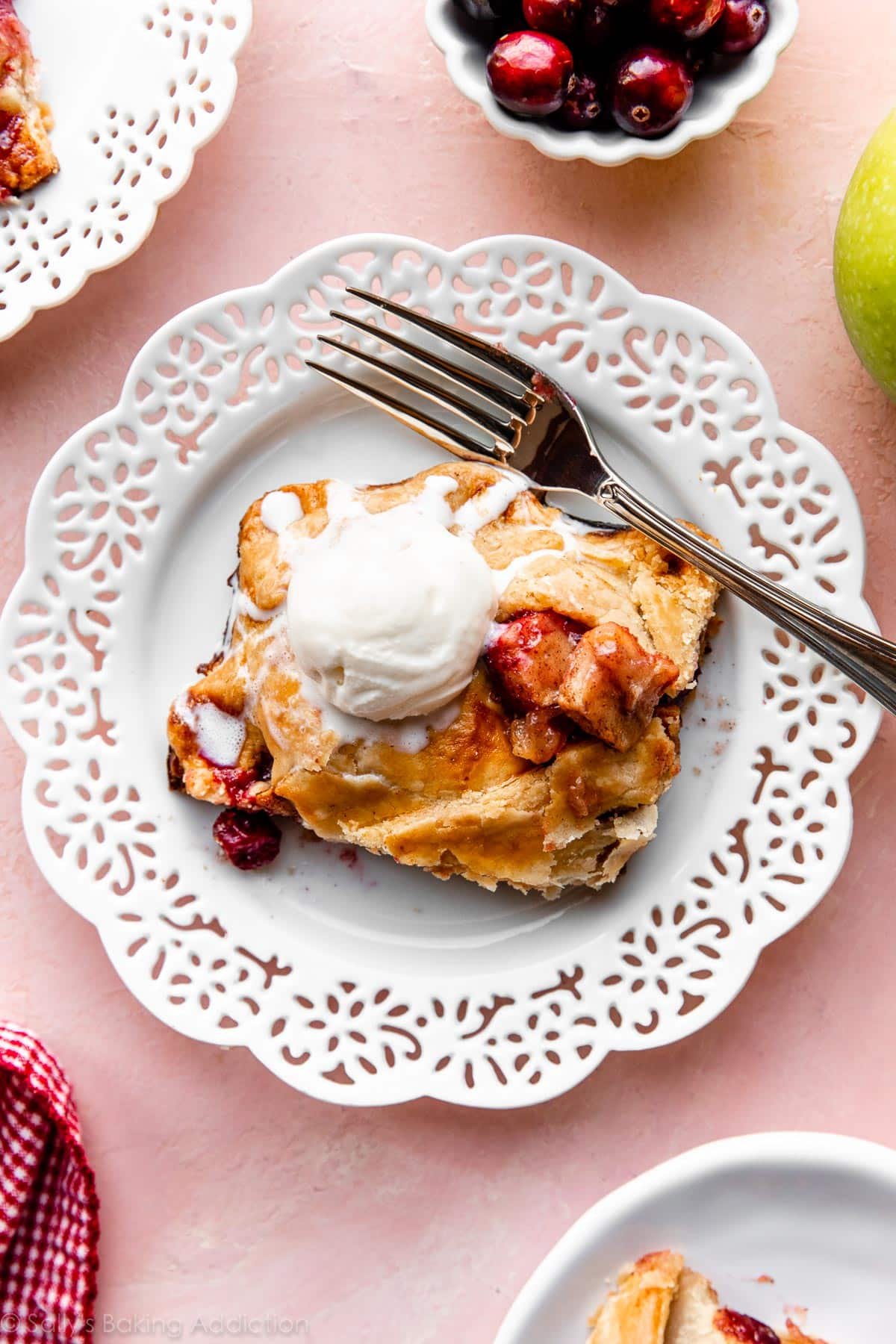 cranberry apple pie serving on white plate with vanilla ice cream