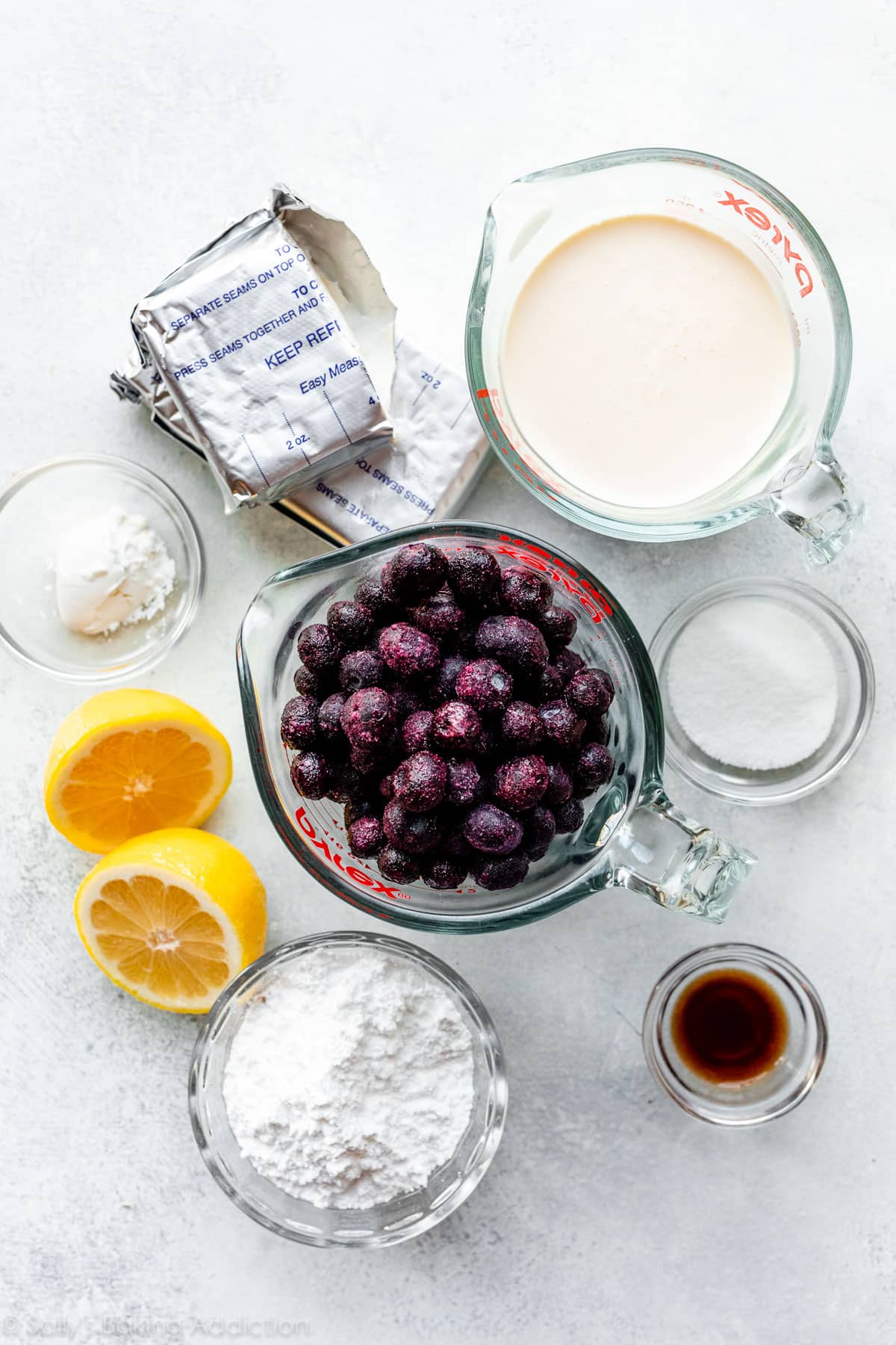 ingredients for recipe including frozen blueberries, heavy cream, lemon cut in half, vanilla extract, sugar, cornstarch, and cream cheese