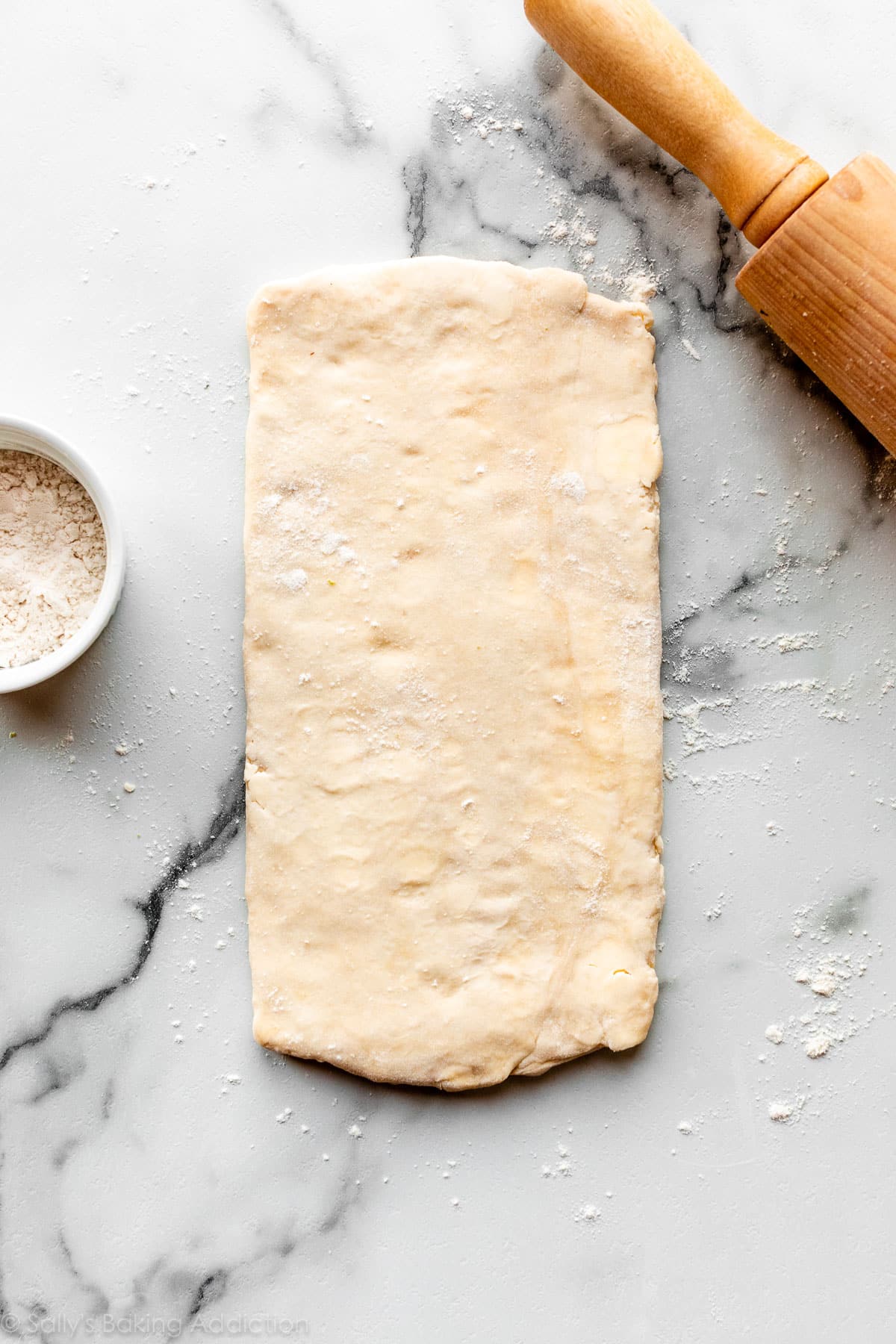 slab of rough puff pastry dough on marble counter