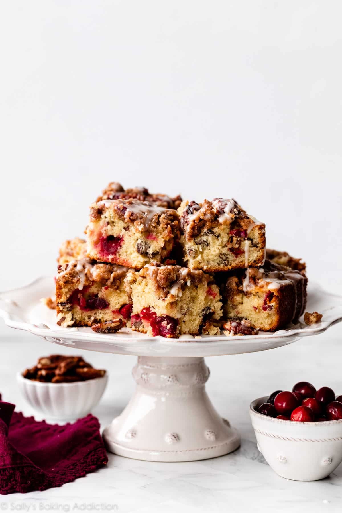 slices of cranberry pecan cake piled on white cake stand