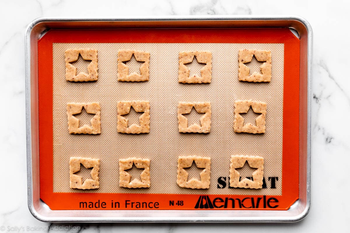square hazelnut cookie dough with a star cut out in the center and arranged on a baking sheet