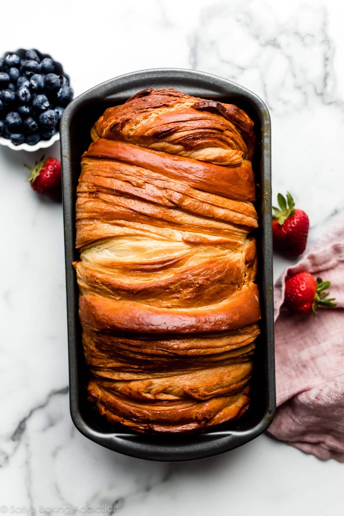 baked croissant bread in loaf pan with berries in background