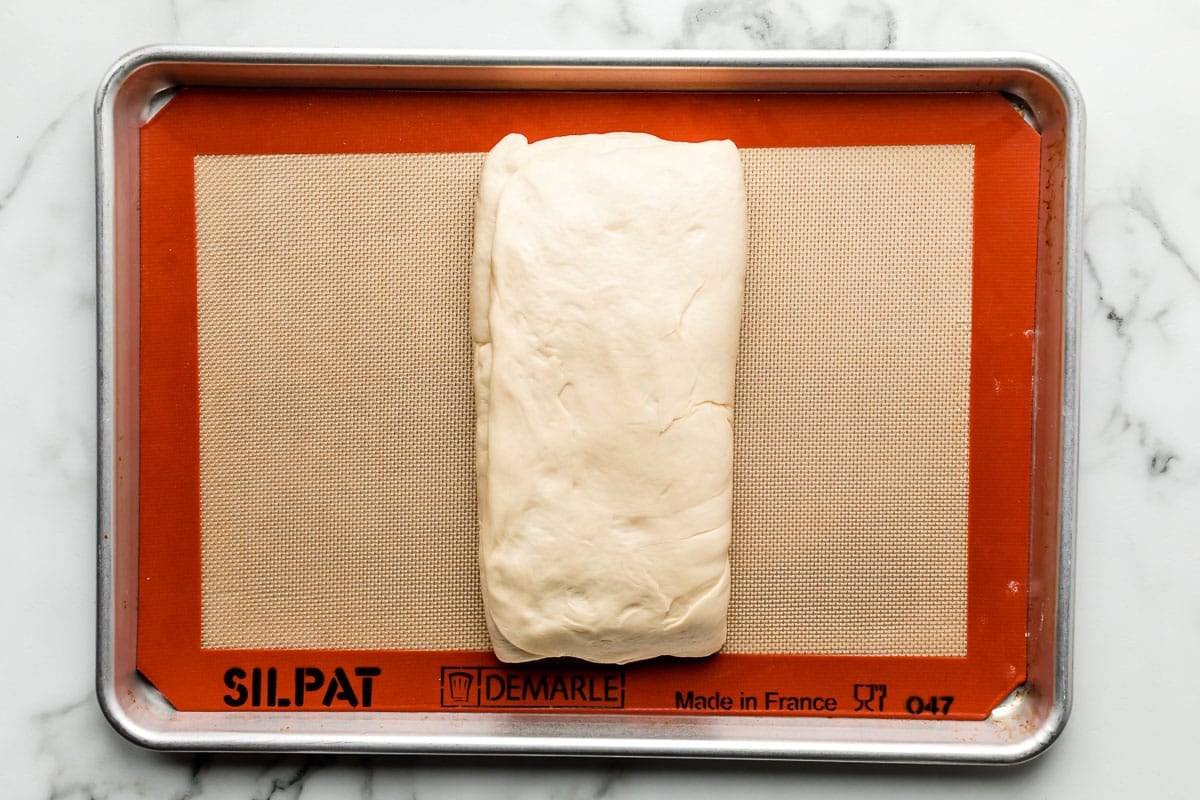 dough folded up on silicone baking mat lined baking sheet