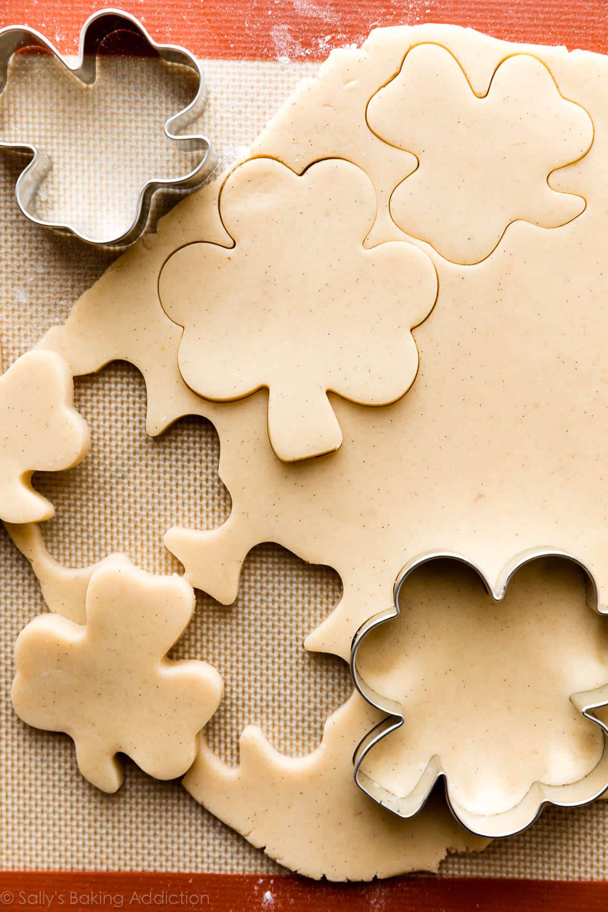 sugar cookie dough cut into shamrock shapes with cookie cutter