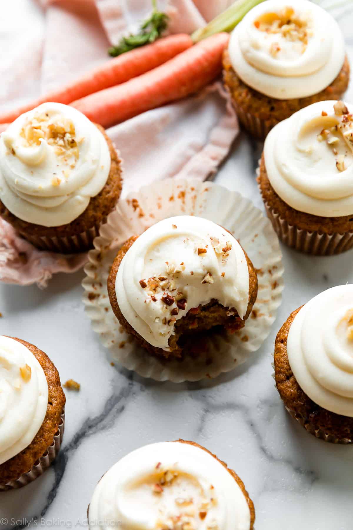 7 carrot cake cupcakes with cream cheese frosting and chopped walnuts on top=