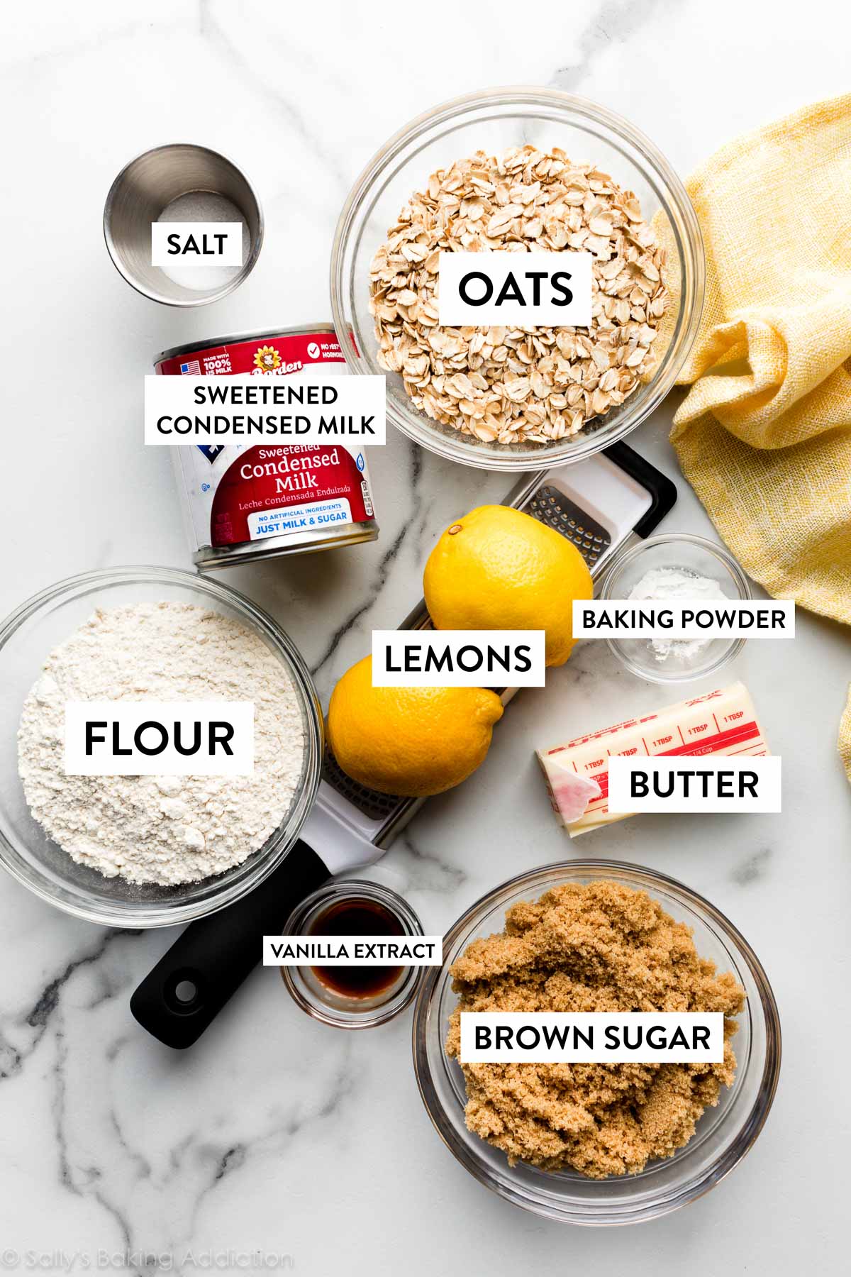 ingredients on marble counter including lemons, oats, sweetened condensed milk, brown sugar, and butter