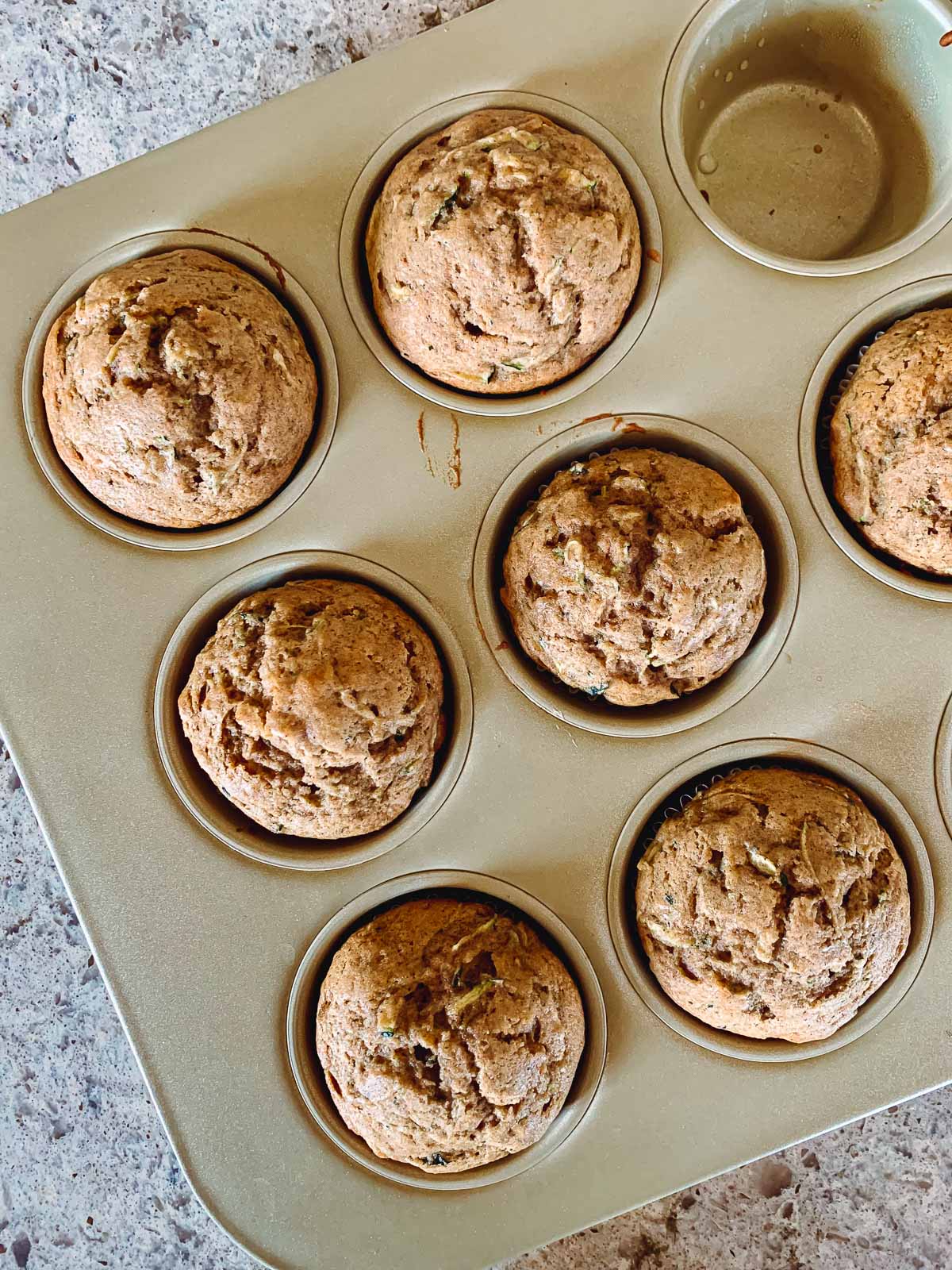 zucchini muffins in gold muffin pan.