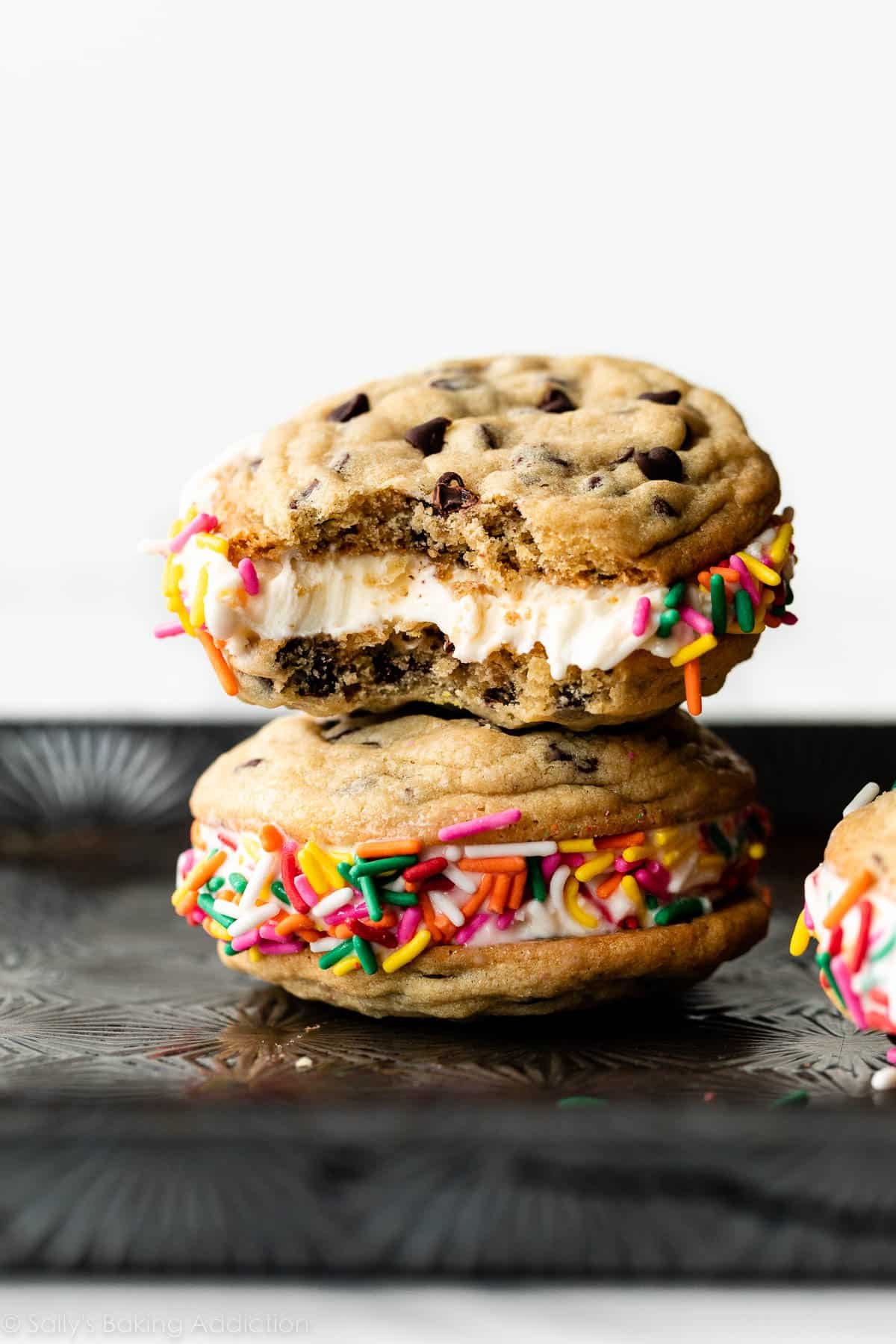 a chocolate chip cookie ice cream sandwich with a bite taken out stacked on another.