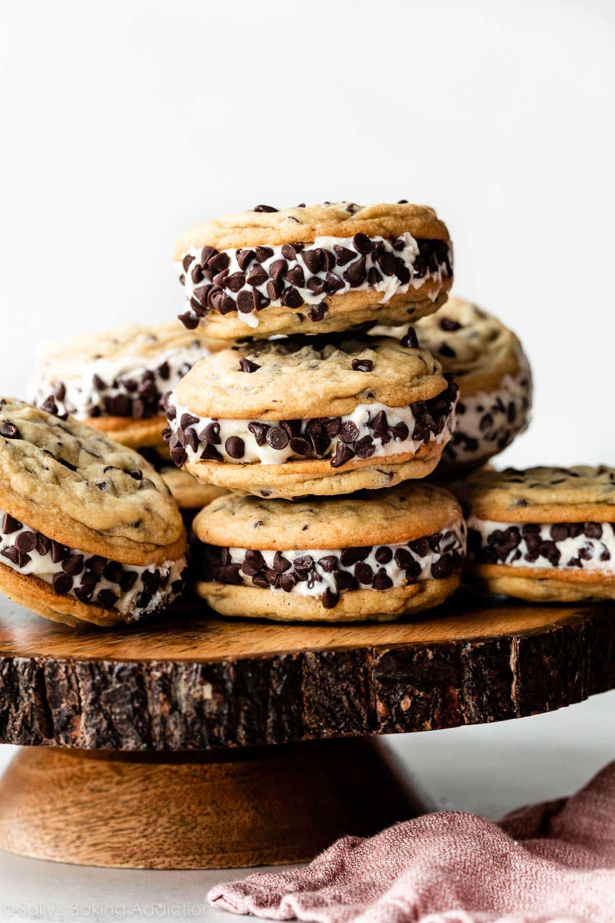 chocolate chip cookie ice cream sandwiches arranged on wooden cake stand.