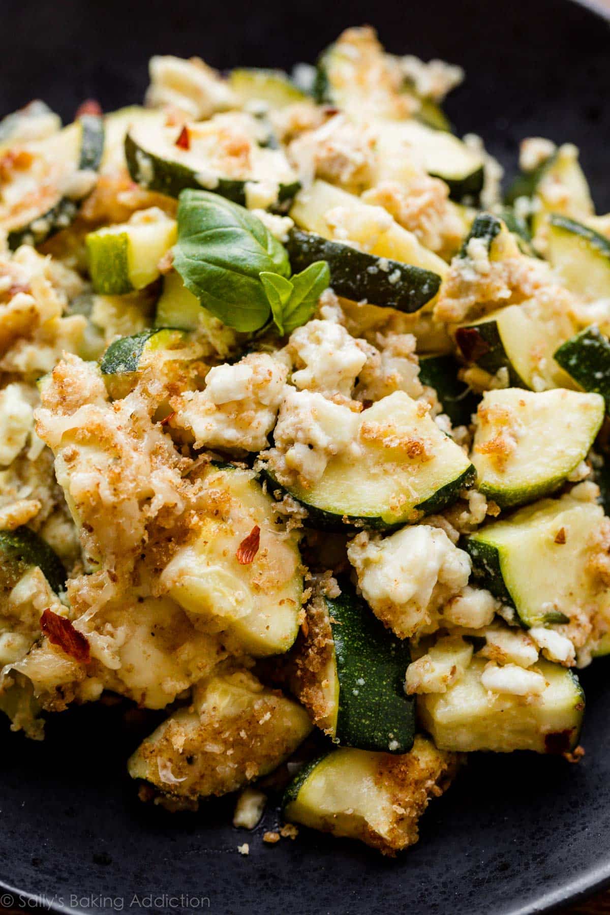 A side dish of baked zucchini feta served on a black plate