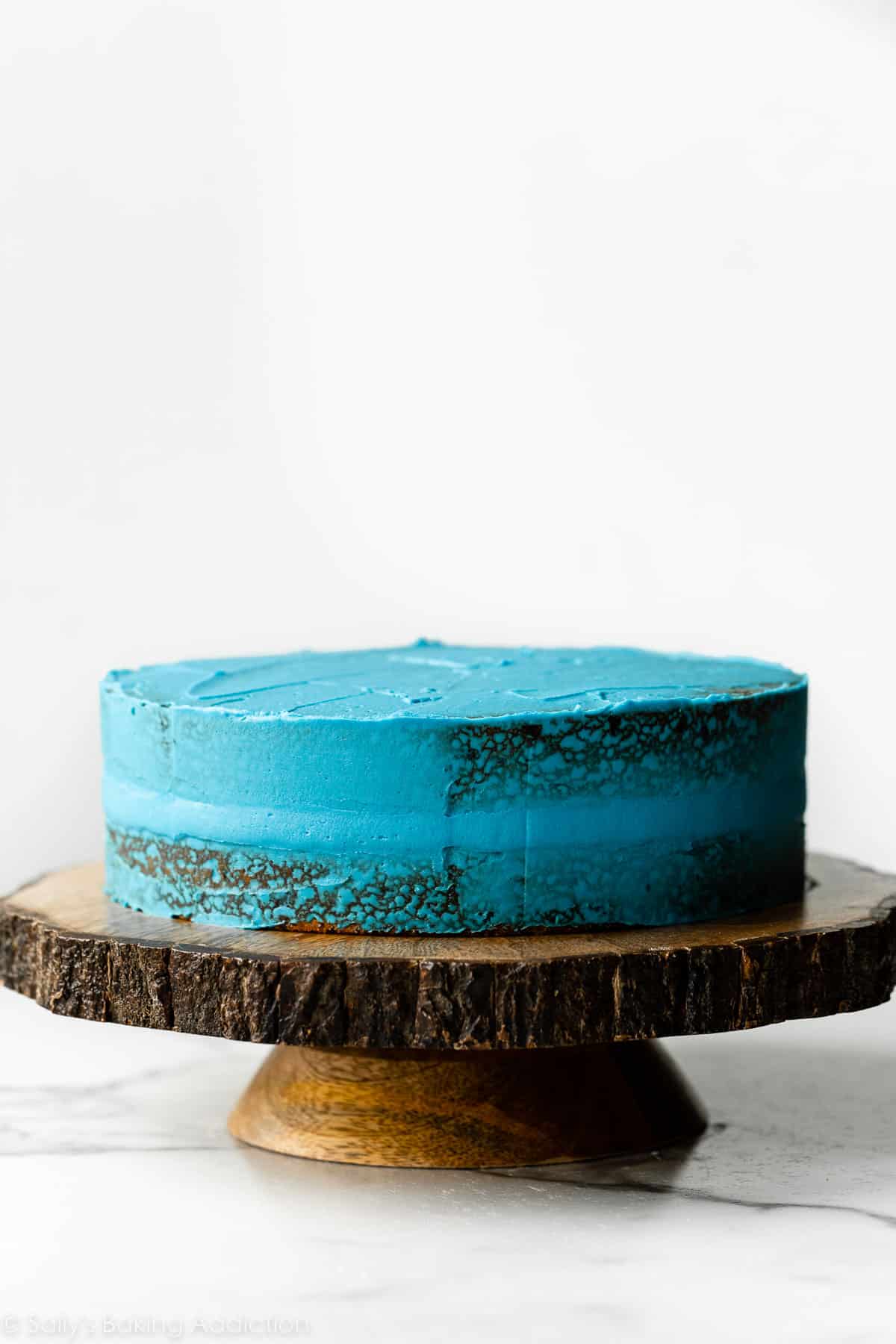 blue crumb coated cake on wooden cake stand.