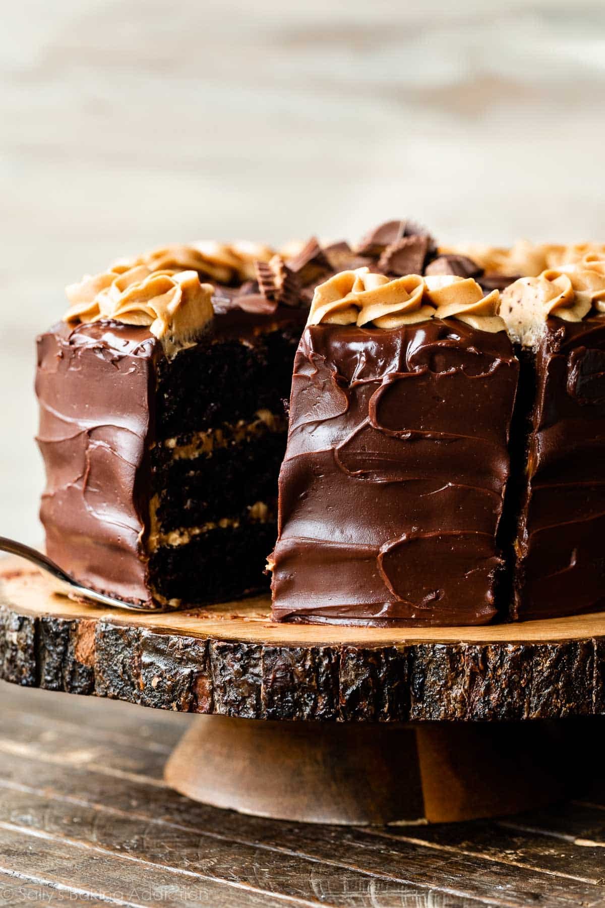 chocolate peanut butter cake frosted with chocolate ganache on wood cake stand.