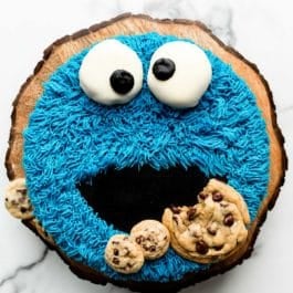 homemade decorated cookie monster cake on wooden cake stand.