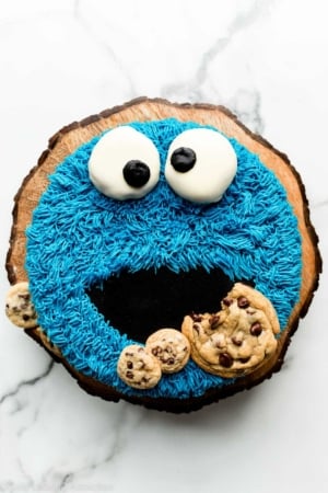 homemade decorated cookie monster cake on wooden cake stand.
