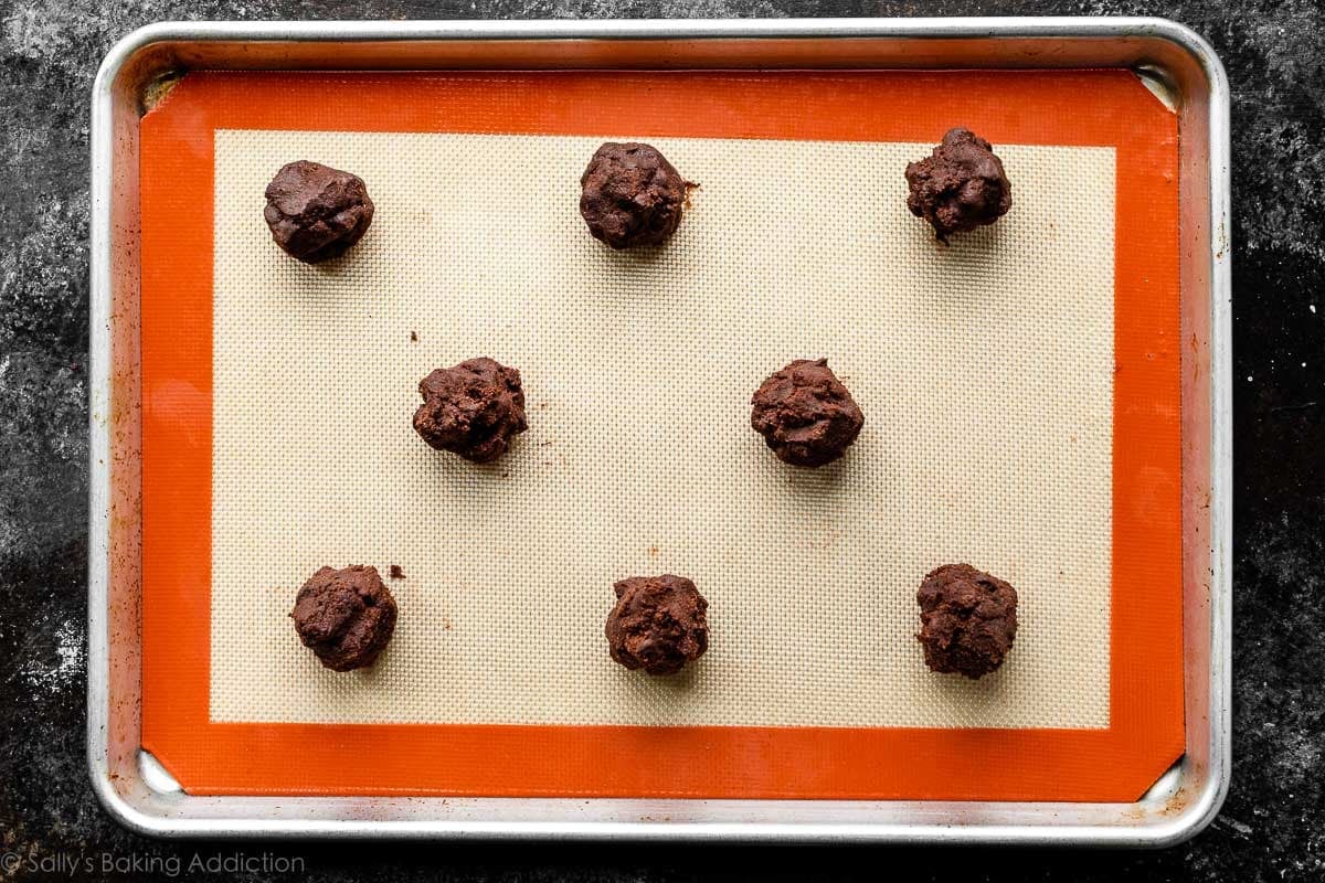 8 chocolate cookie dough balls on Silpat lined baking sheet.