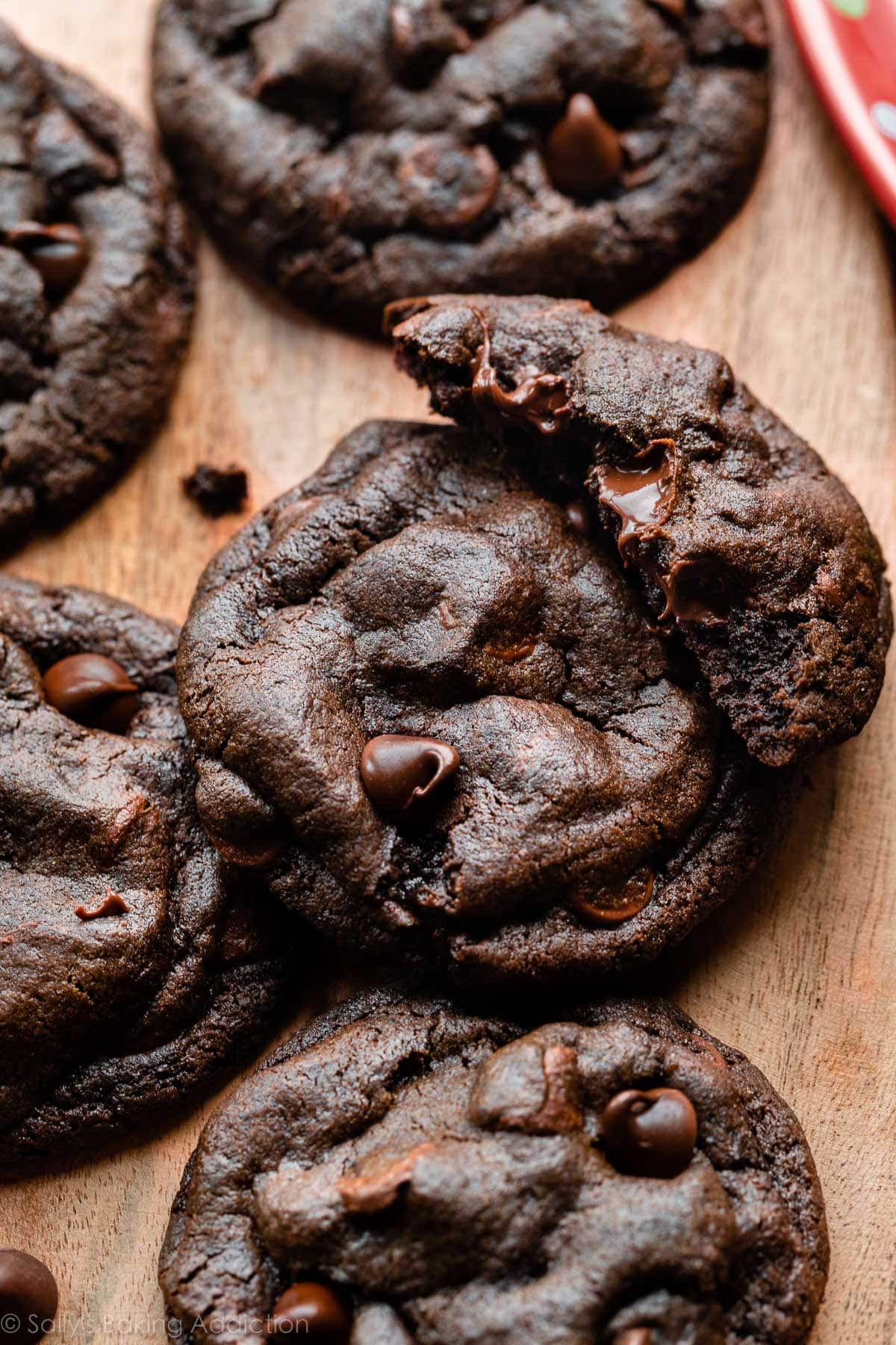double chocolate chip cookies on wooden surface with one broken in half.