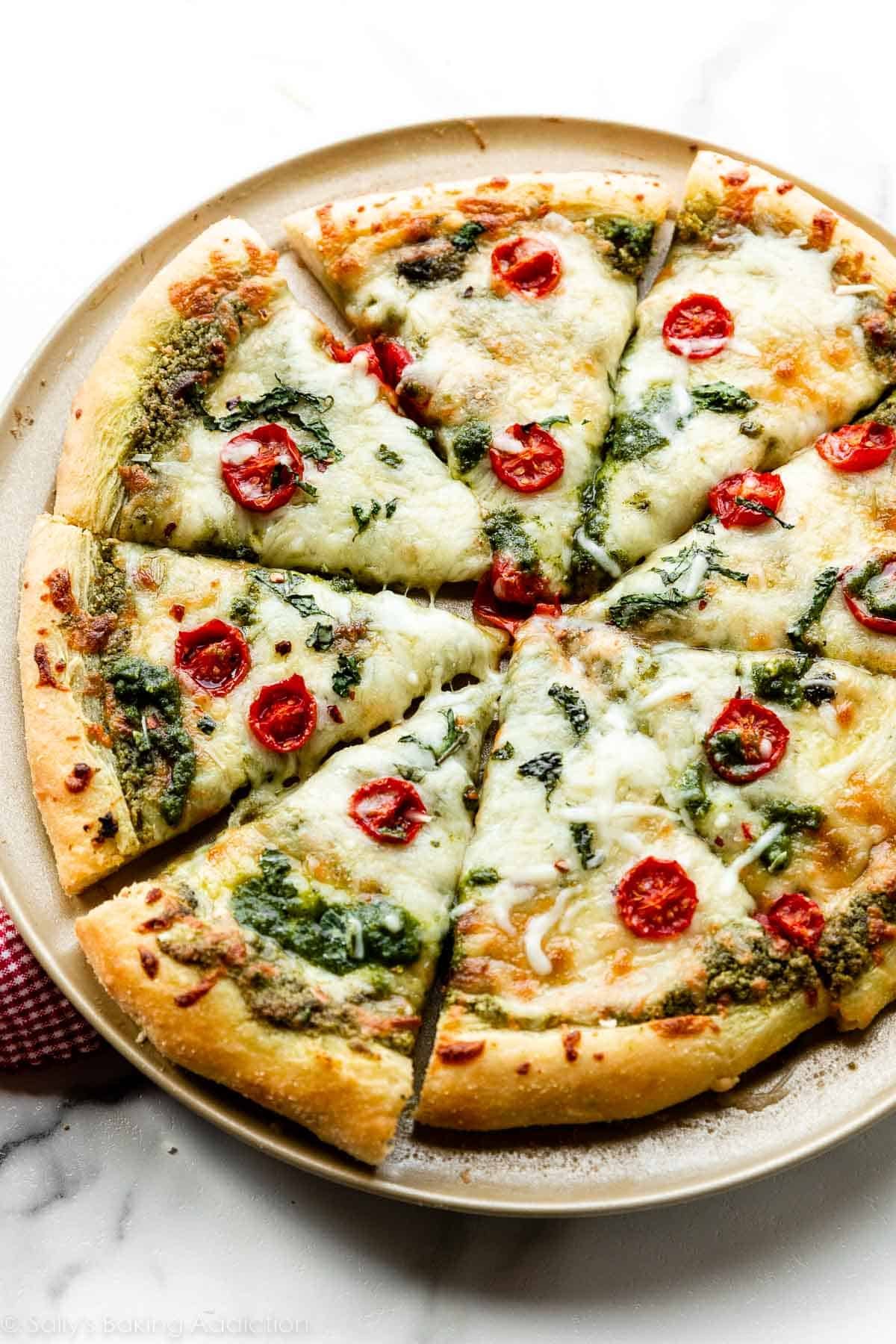 baked and sliced pesto pizza with mozzarella cheese and tomatoes.
